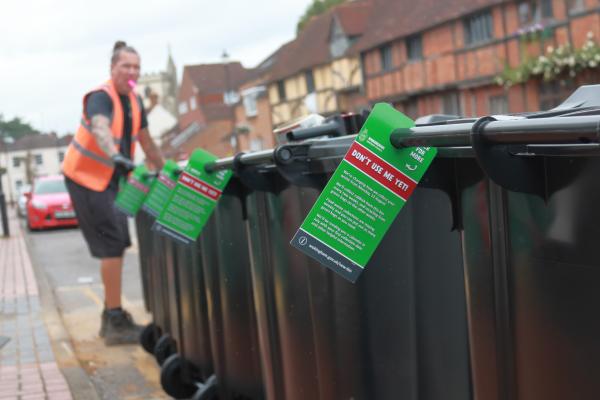 A row of assembled wheelie bins in the street, with tags attached telling people not to use them until August