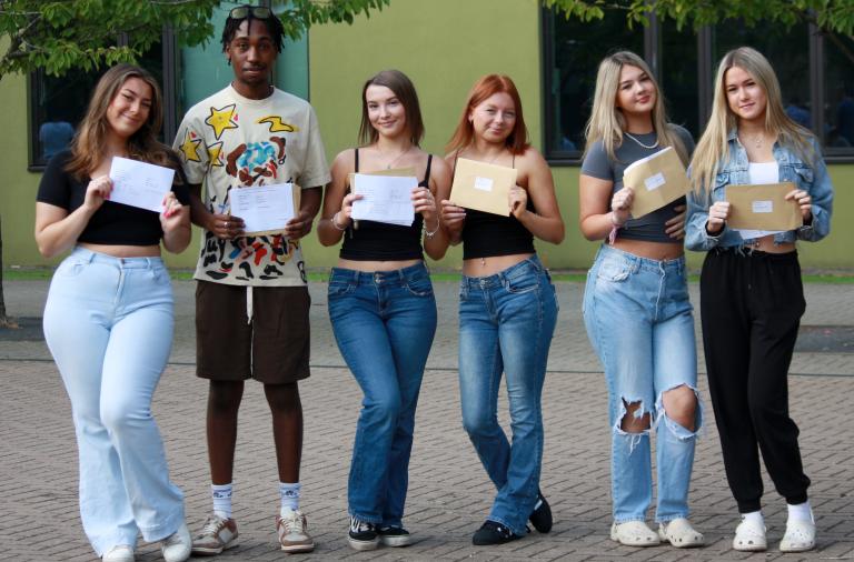 Five girls and one boy from Waingels College stand in a line and hold their exam results up