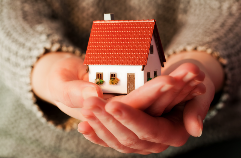 A person holding a small toy house in their hands