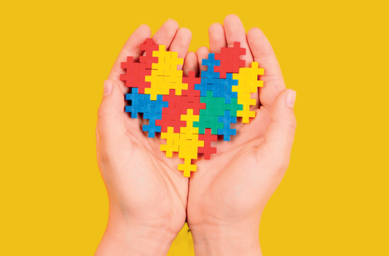 Cupped hands holding a heart shape made from different brightly coloured toy bricks