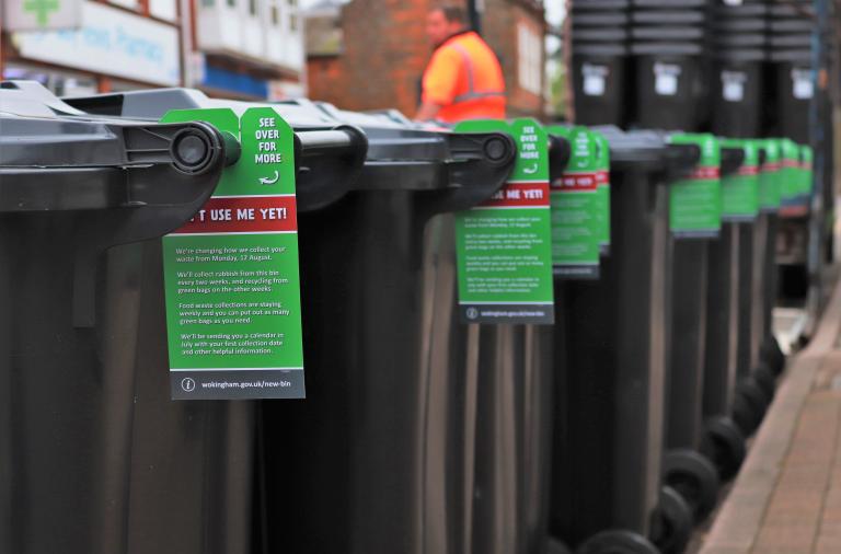 A row of assembled wheelie bins in the street, with tags attached telling people not to use them until August