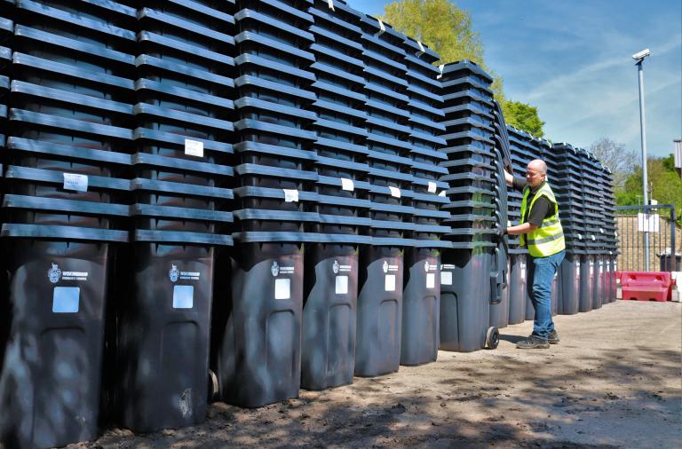 Man stacking new Wokingham Borough Council black wheelie bins