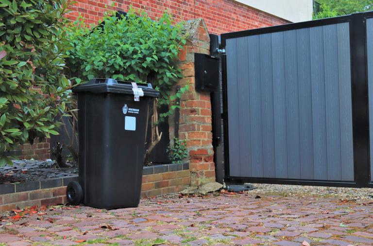 A newly delivered wheeled bin standing on someone's paved driveway