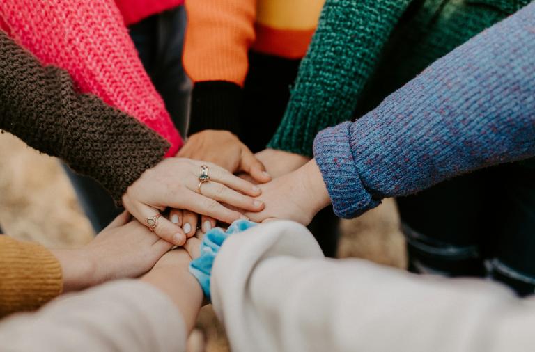 A group circle of hands in the middle to symbolise community