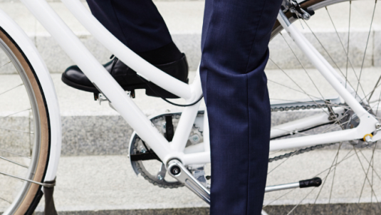 A person in suit trousers and smart shoes sat on a bicycle