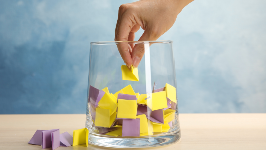 Hand reaching into a bowl to pick a winning ticket