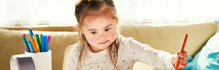 Young girl with down syndrome colouring with a red felt tip